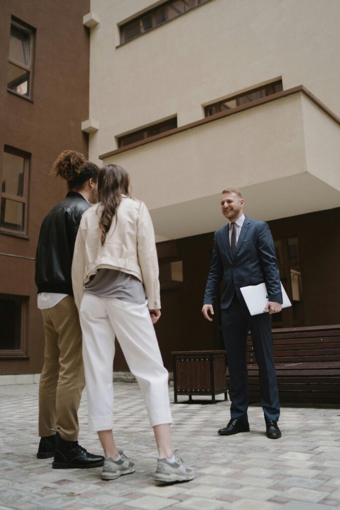 A professional realtor showing a new apartment to a young couple in a city setting.